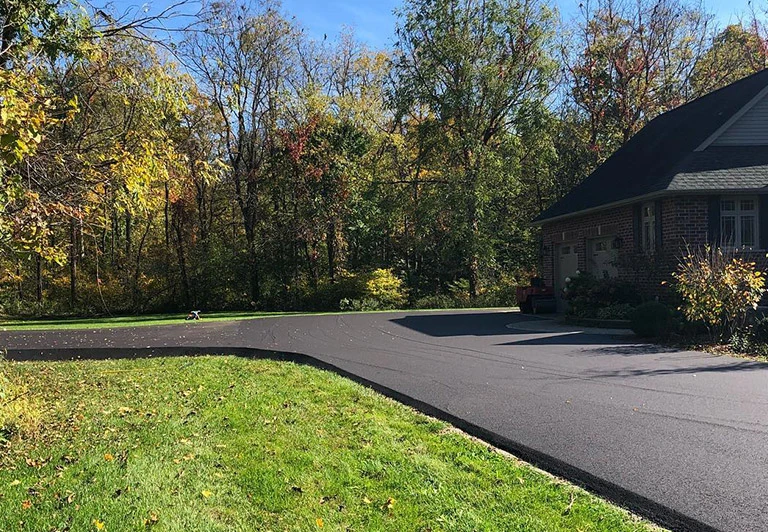 Newly installed asphalt driveway with custom curved edges and smooth finish for a residential property in Oxford County.