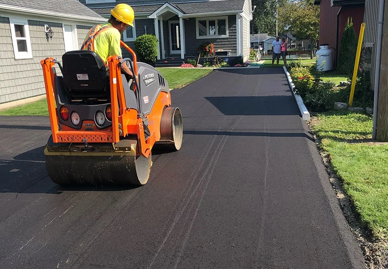 Peters Paving crew using a heavy-duty asphalt roller for proper compaction on a residential driveway in Middlesex County.