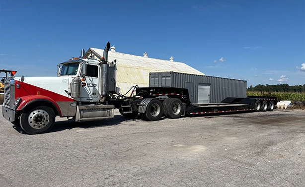 Peters Paving heavy-duty transport truck floating a 40-foot industrial storage container on a multi-axle flatbed trailer.