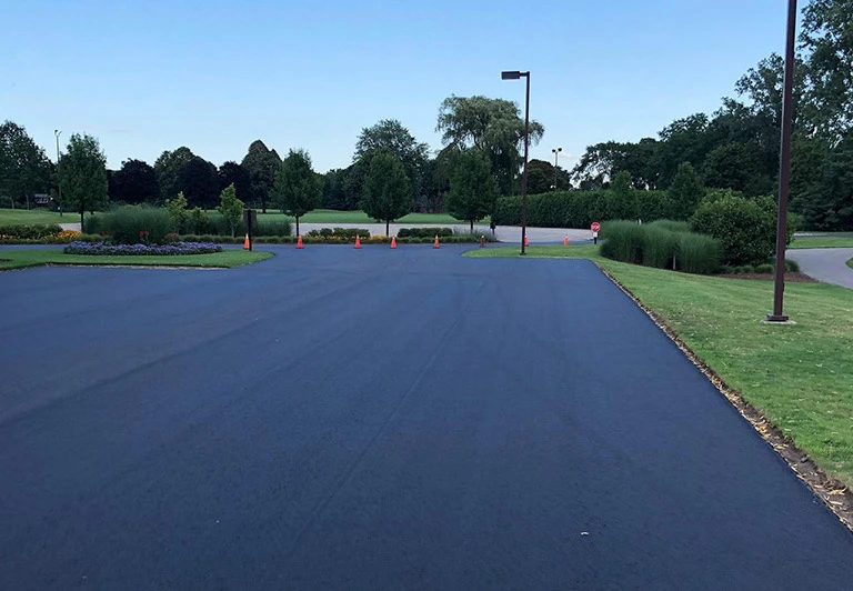 Finished asphalt parking lot for a landscaped commercial property featuring professional edging and orange safety cones.