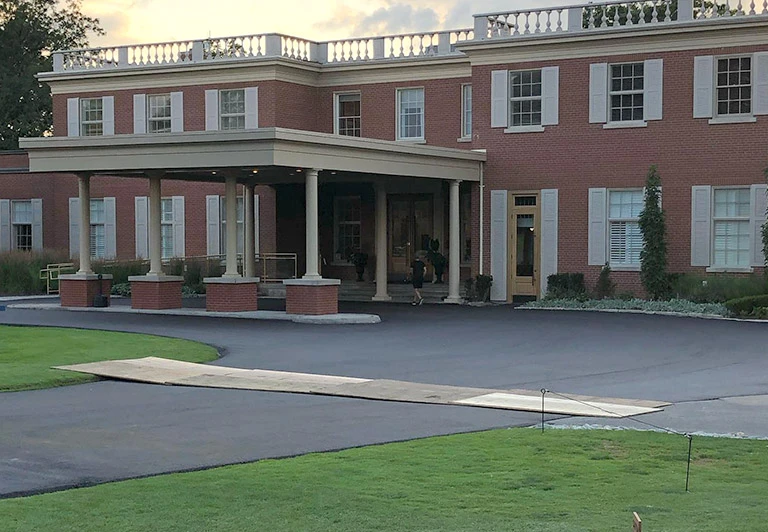 Freshly paved asphalt driveway and porte-cochère entrance for a luxury commercial estate building.