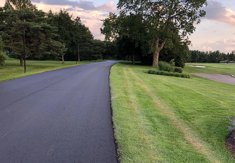 Smoothly paved asphalt access road and parking area for a high-end golf course and country club.